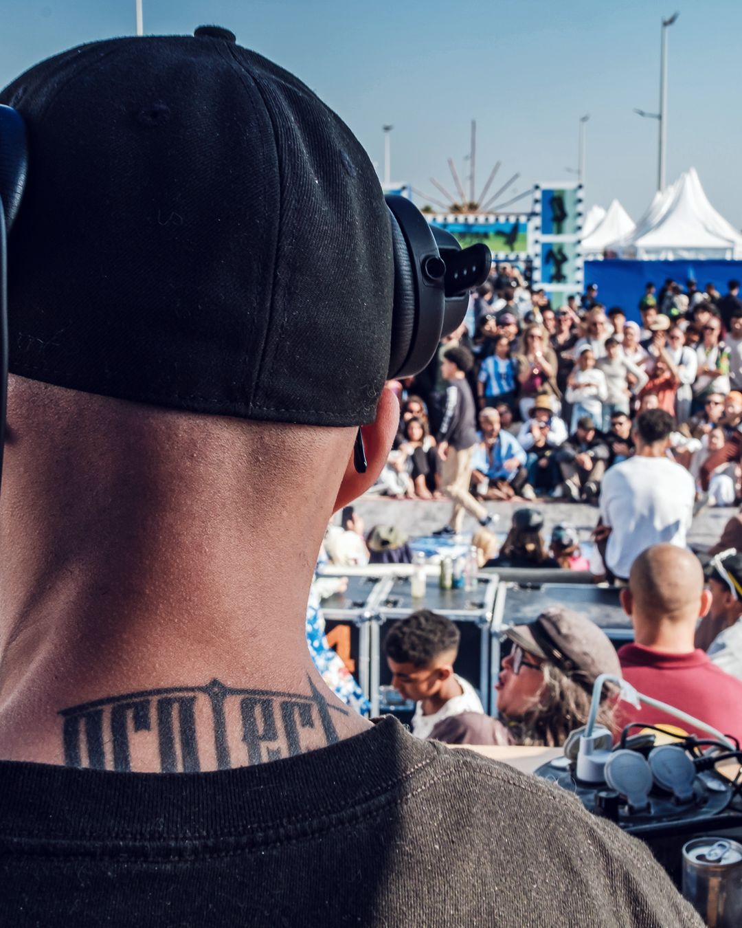 Le DJ du battle, casque sur les oreilles, face au cercle et à la foule de la corniche, en 2026