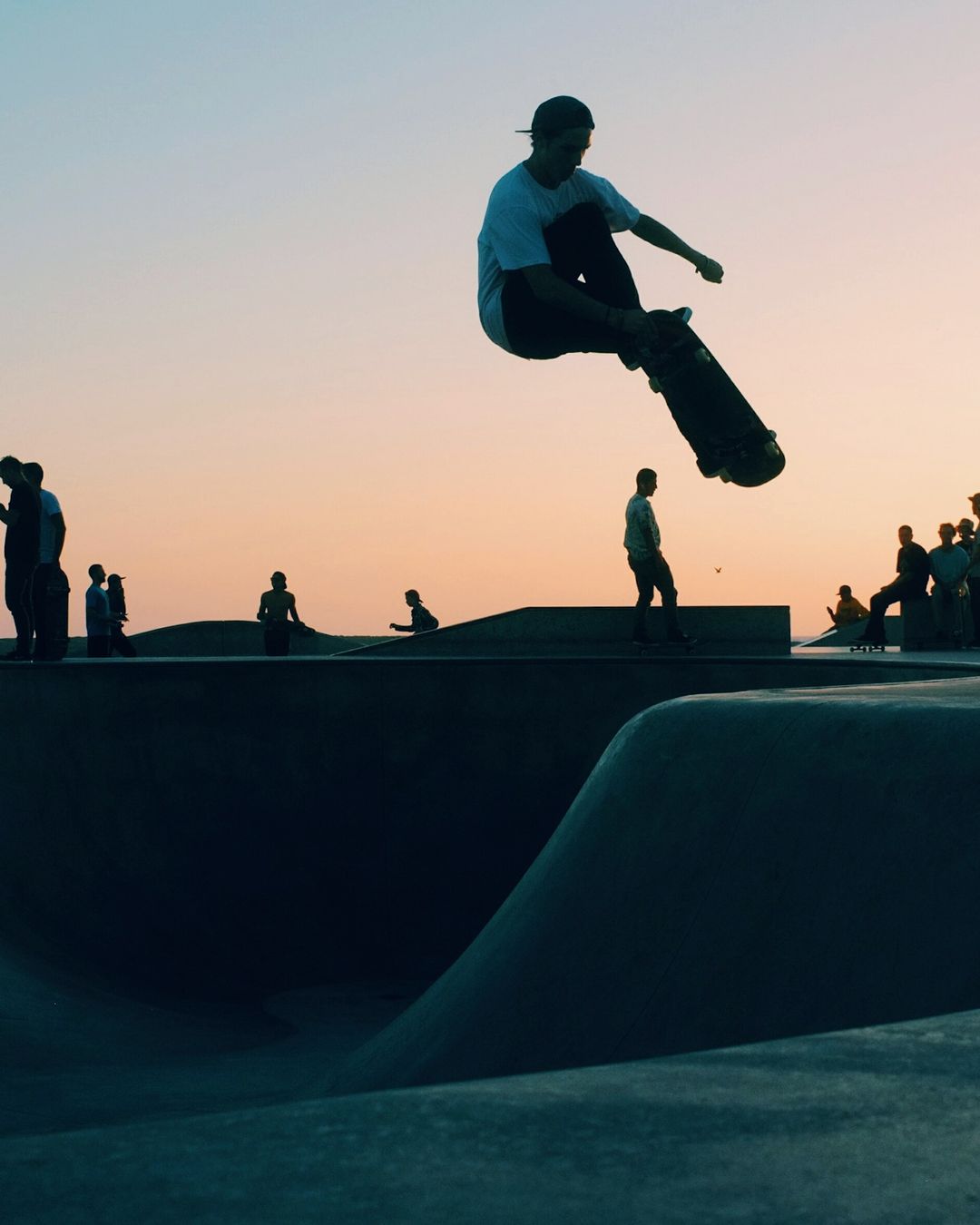 Un skateur s'envole au-dessus d'un bowl en béton, au coucher du soleil (photo d'illustration)