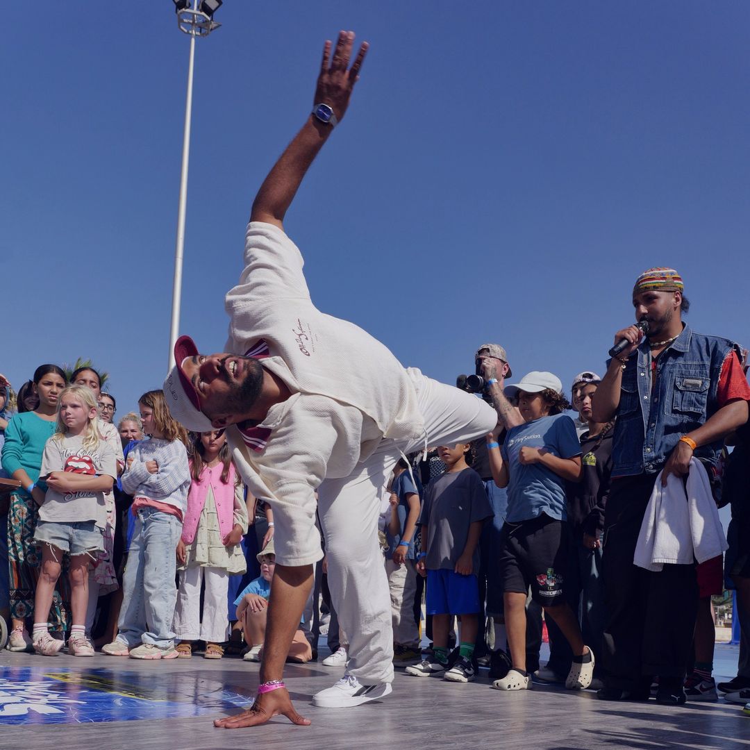 Un danseur en blanc figé sur une main, devant la foule