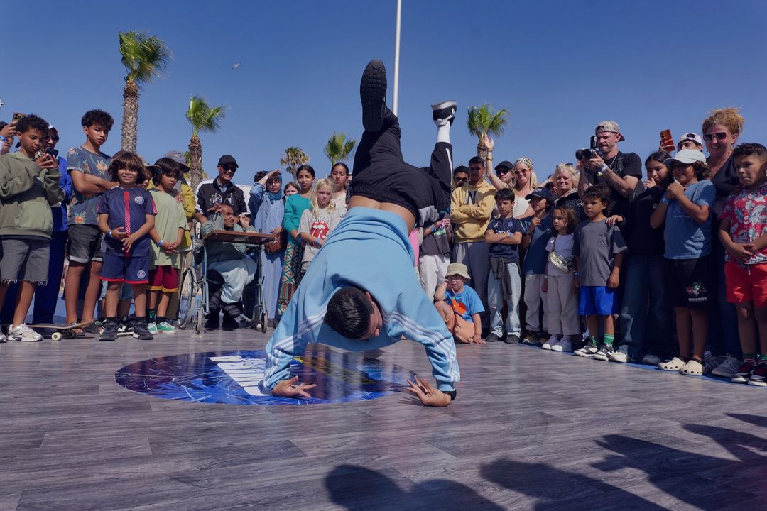 Un danseur au sol au centre du cercle, entouré du public